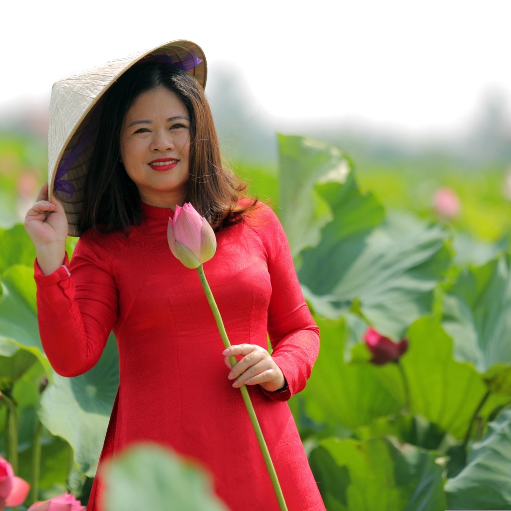 Девушка азиатка в красном платье у цветов лотоса