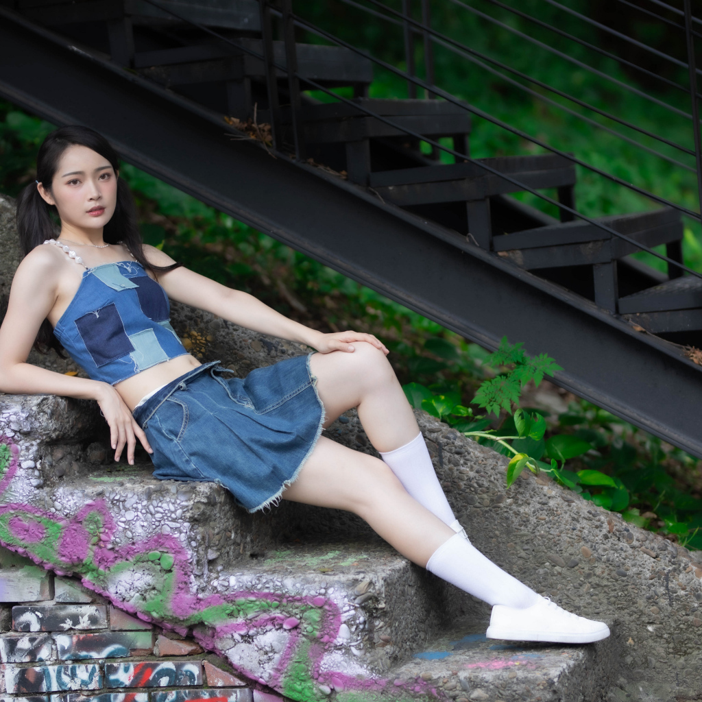 Девушка азиатка в юбке лежит на лестнице