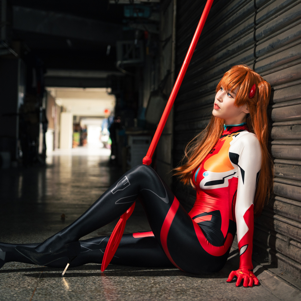 Девушка азиатка в костюме сидит у стены