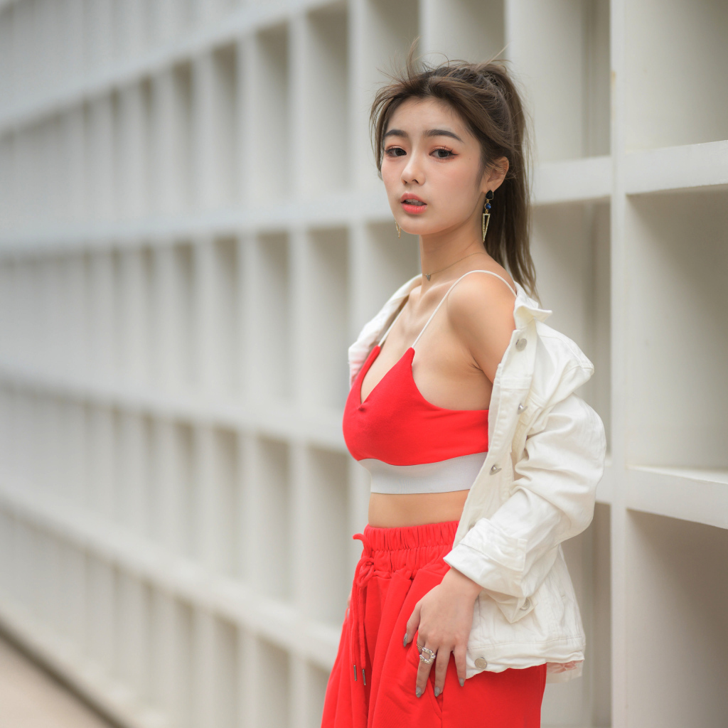 Азиатка в красном спортивном костюме стоит у стены