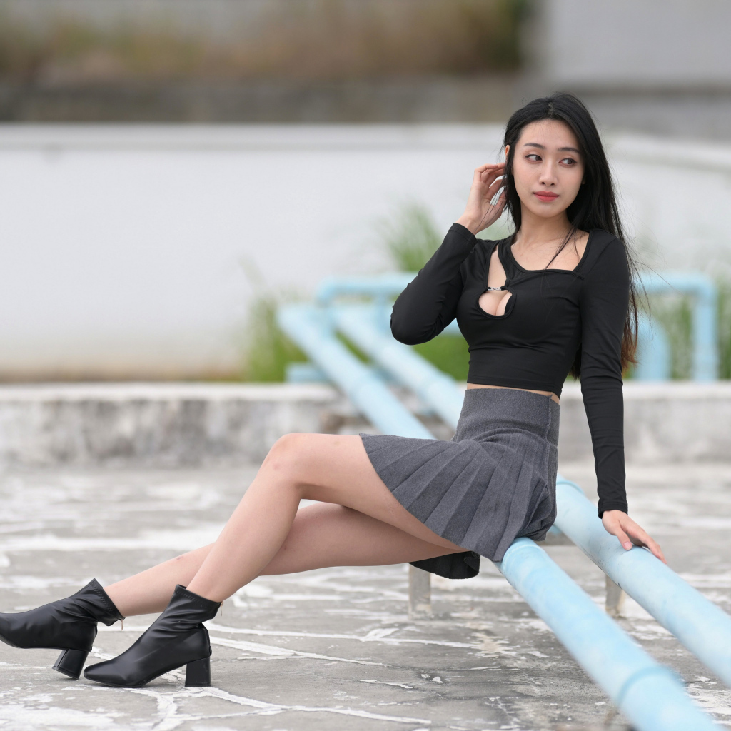 Азиатка в короткой юбке сидит на трубе