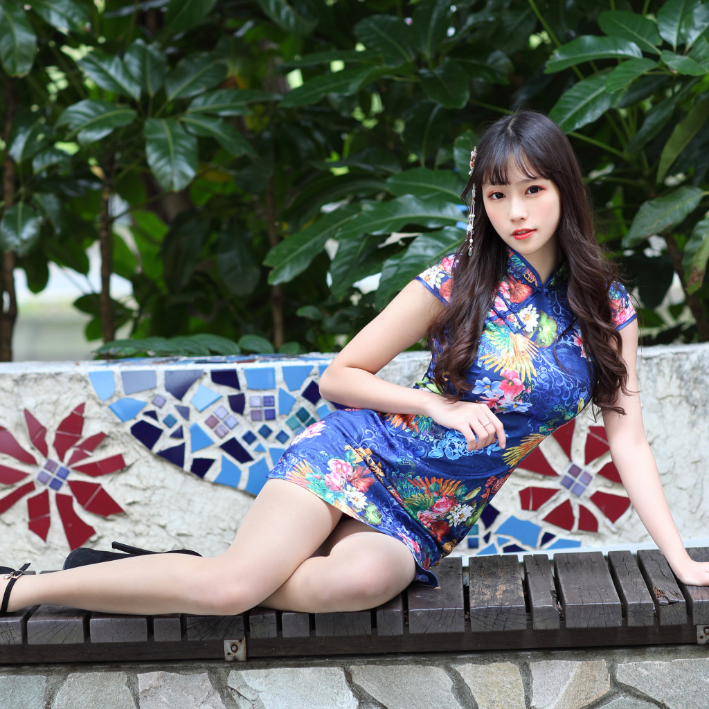 Красивая девушка азиатка в платье лежит на лавке