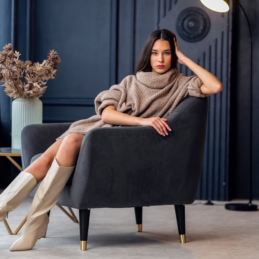 Красивая брюнетка в сапогах сидит в кресле