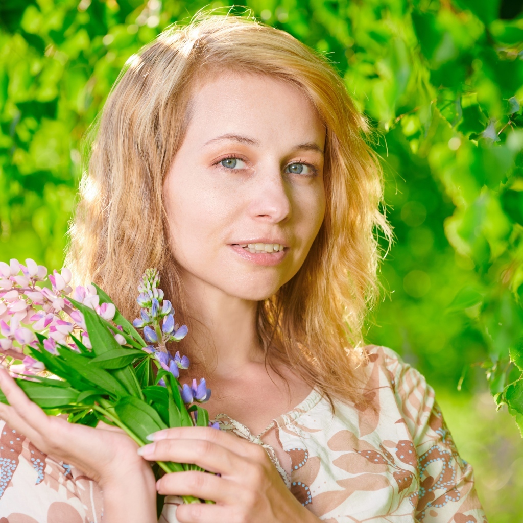 Красивая девушка с цветами люпина в руке