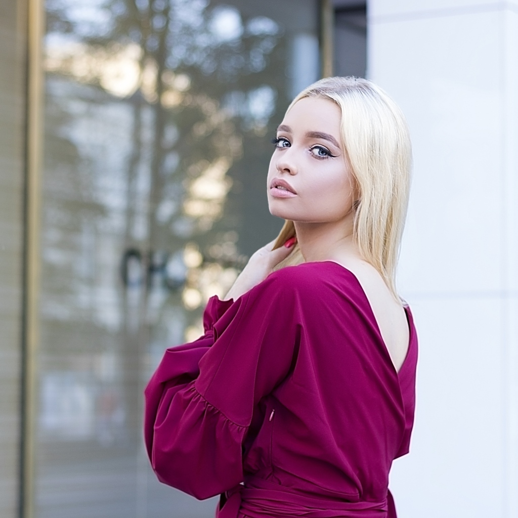 Милая девушка блондинка в платье стоит у здания