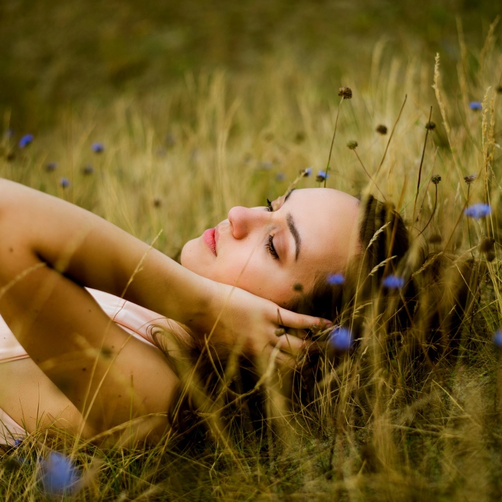 Милая девушка лежит на траве на поле