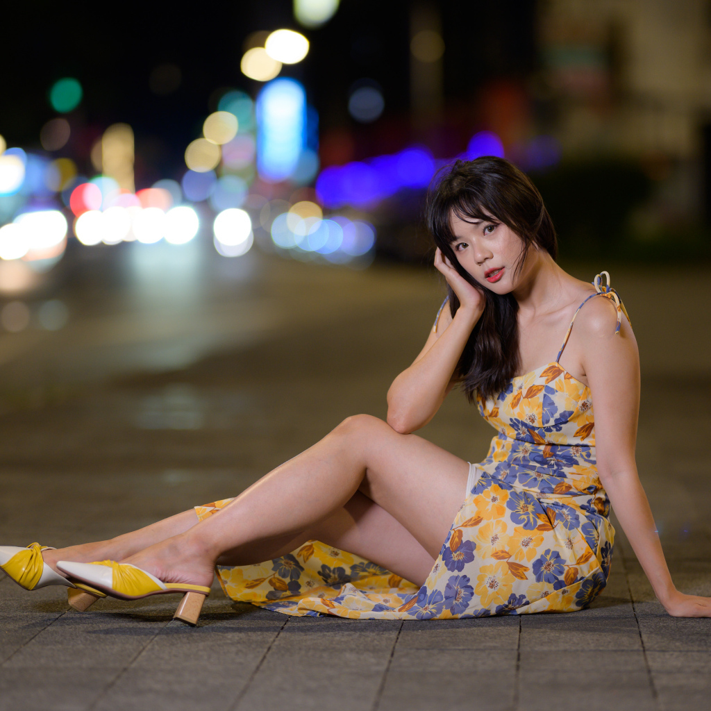 Милая нежная азиатка в платье сидит на дороге