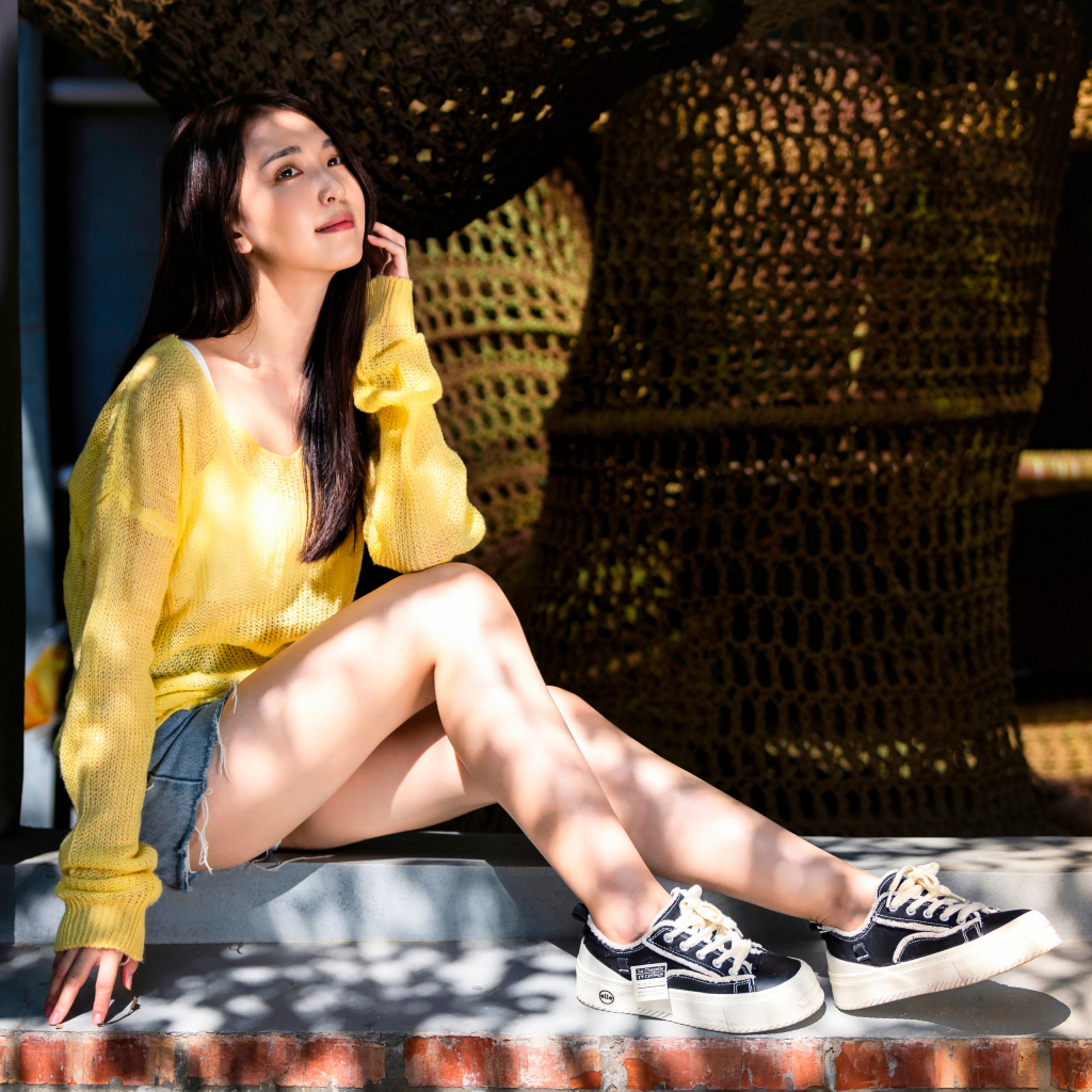 Мечтательная молодая девушка азиатка сидит на окне