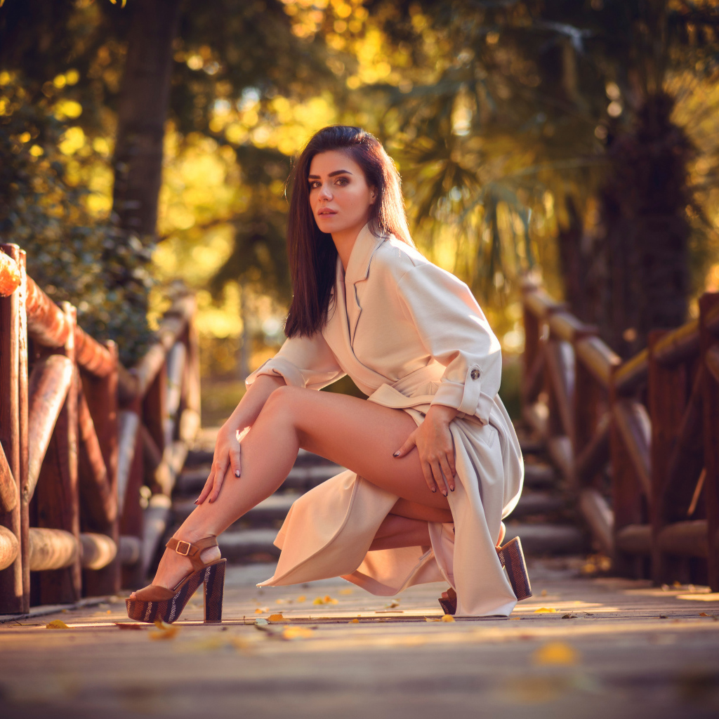 Девушка в пальто на мосту в парке 