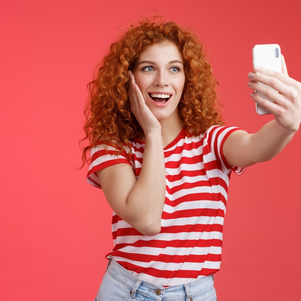 Девушка делает селфи на красном фоне