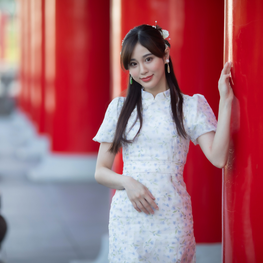 Длинноволосая азиатка позирует у красной колонны