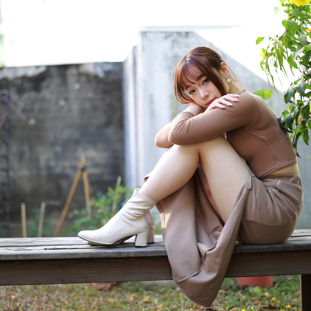 Скромная молодая азиатка сидит на лавке