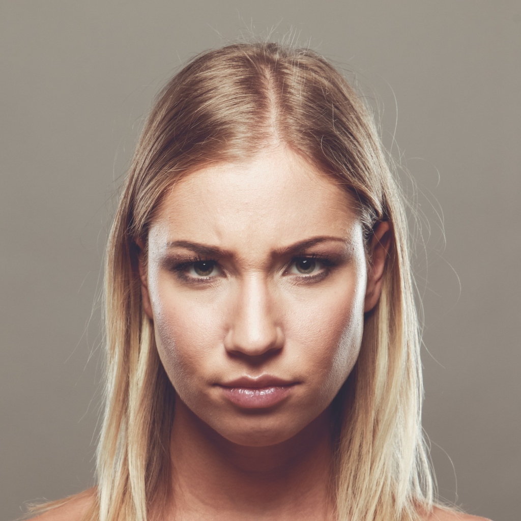 Серьезная девушка с короткой стрижкой на сером фоне