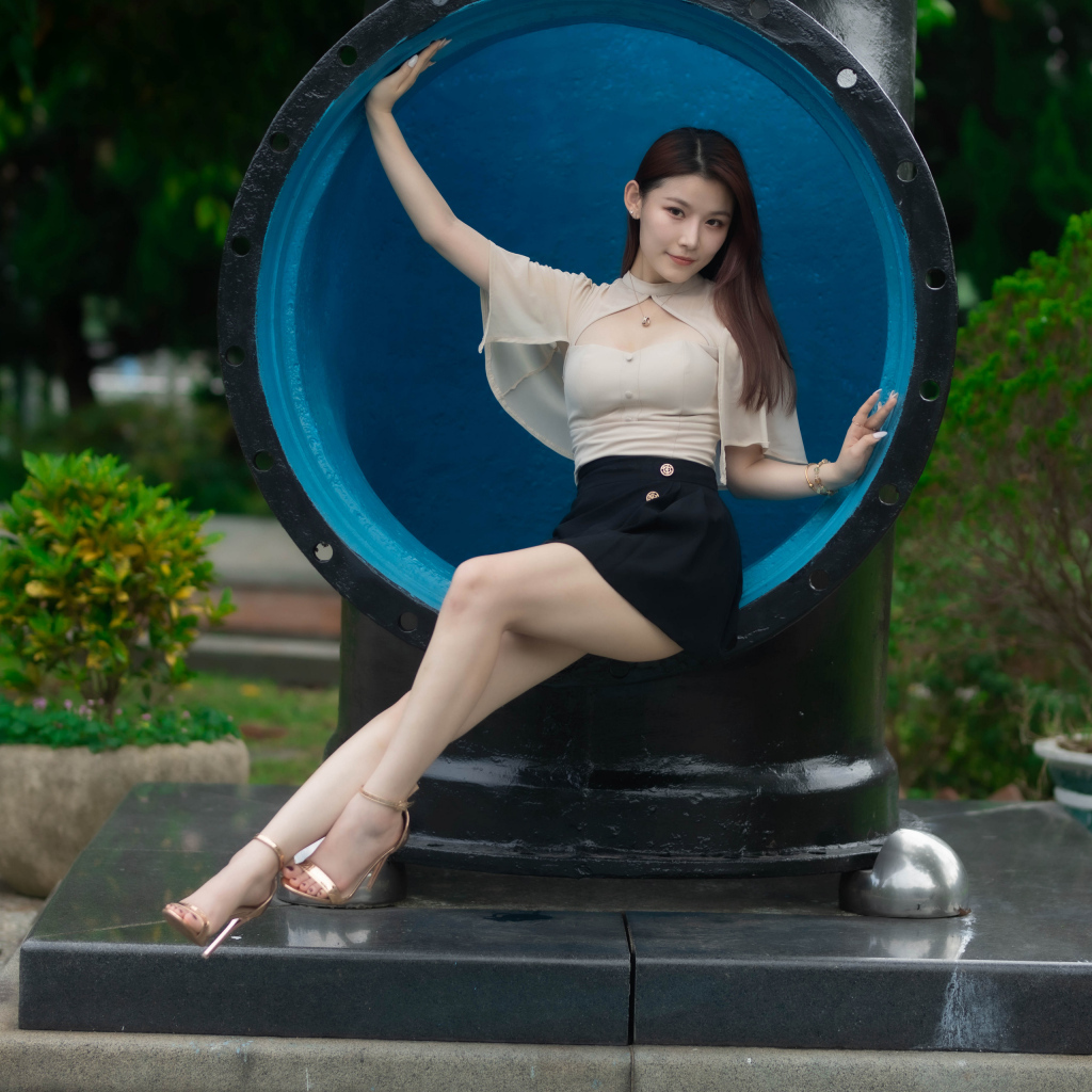 Стройная длинноногая азиатка сидит в трубе