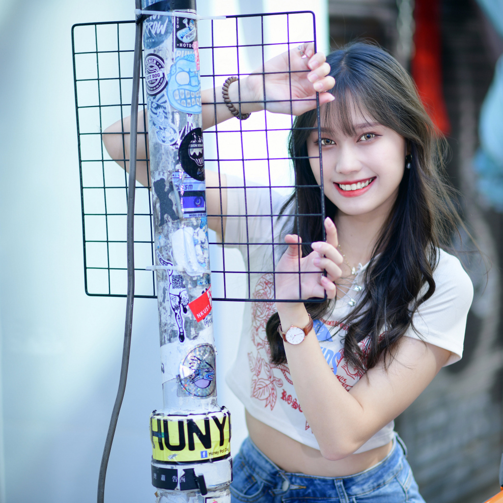 Улыбающаяся азиатка держится за сетку