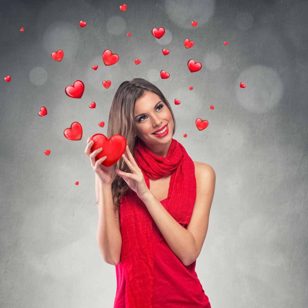 Улыбающаяся девушка в красном платье с сердечками на сером фоне