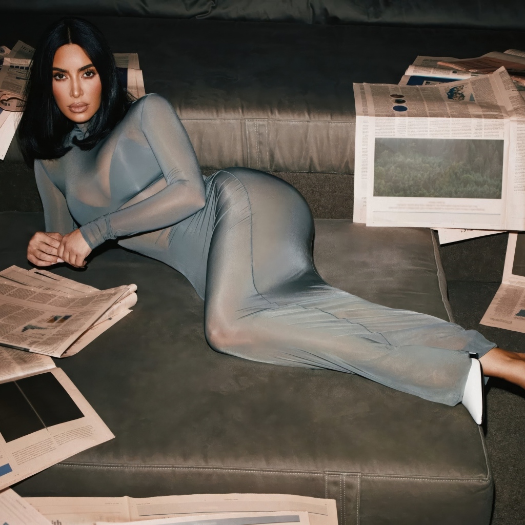 Модель Ким Кардашьян лежит на диване с газетами