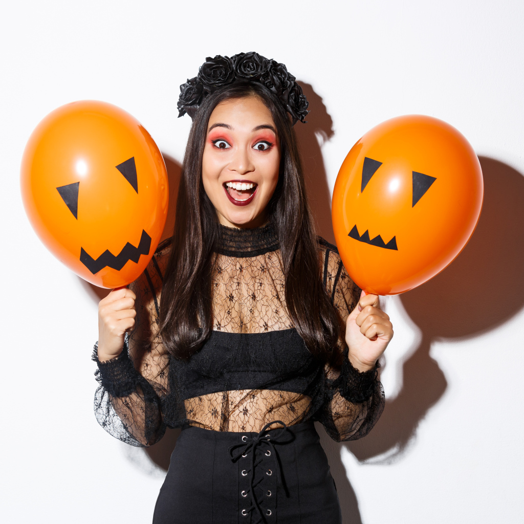 Девушка в костюме на праздник Хэллоуин с шариками в руках