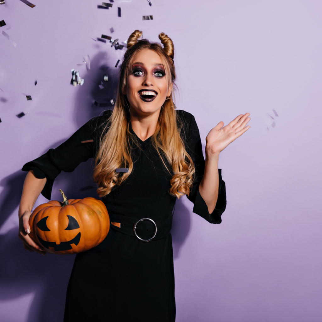 Девушка в черном костюме с тыквой на праздник Хэллоуин