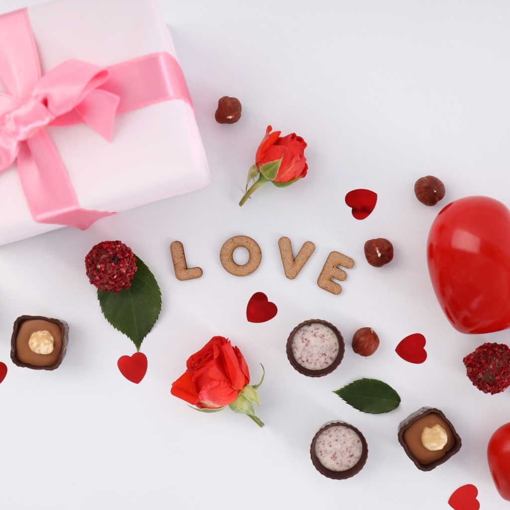 Подарок и сердечки с конфетами на столе на День Святого Валентина