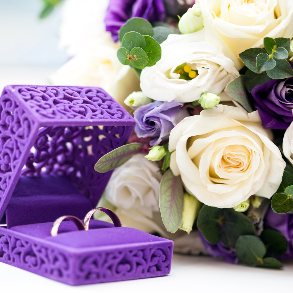 Красивая коробочка с кольцами и букетом цветов на столе