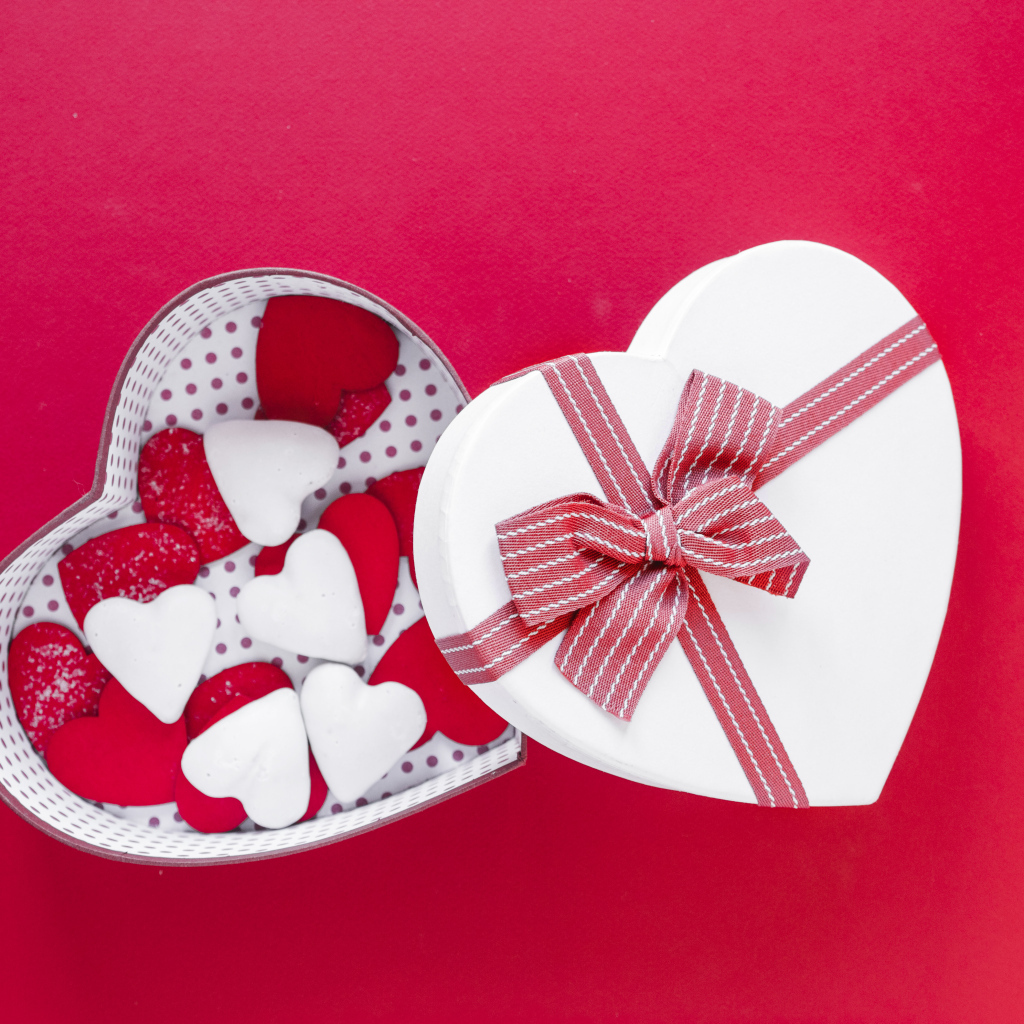 Красивая коробка наполнена сердечками на красном фоне