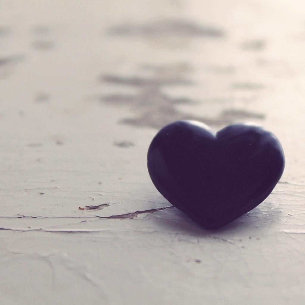 Черное каменное сердце на деревянной поверхности 