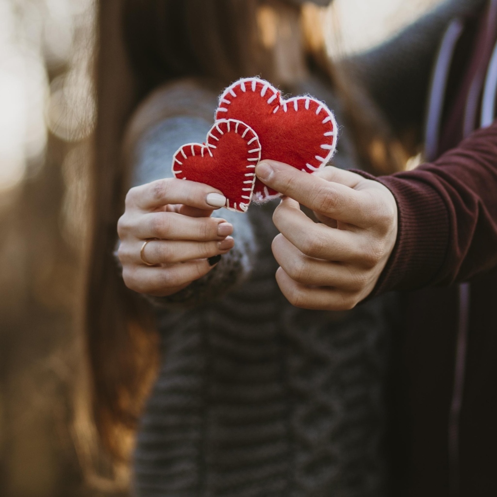 Влюбленная пара держит сердечки в руках