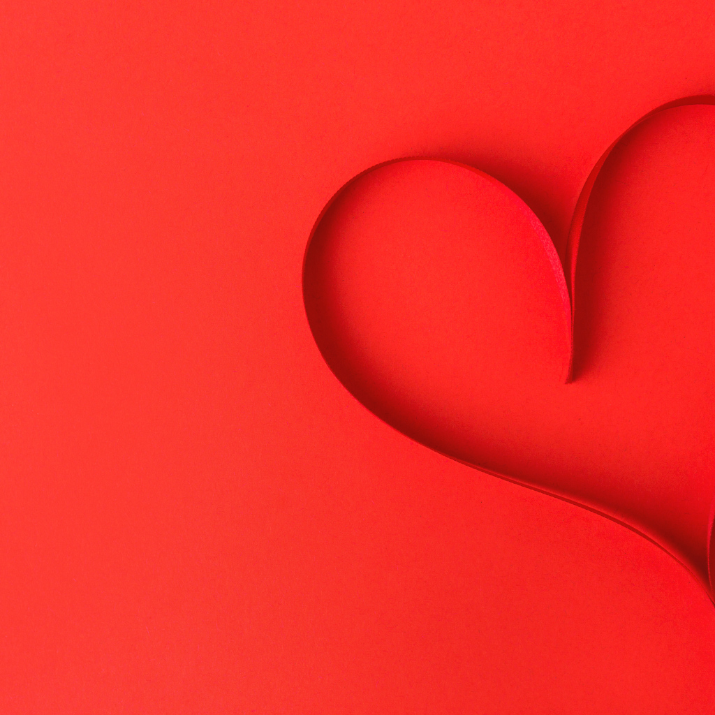 Сердце из атласной ленты на красном фоне