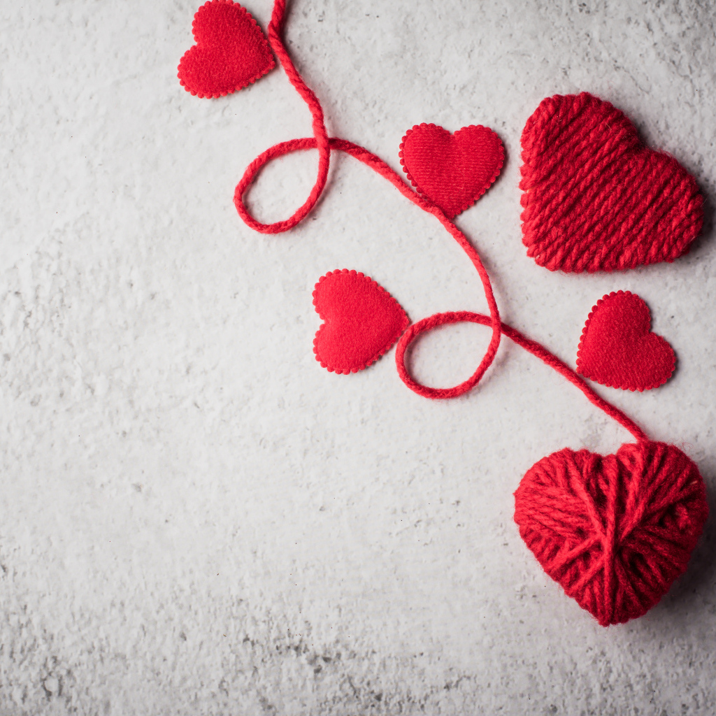 Сердечки из красной шерстяной нити на сером фоне