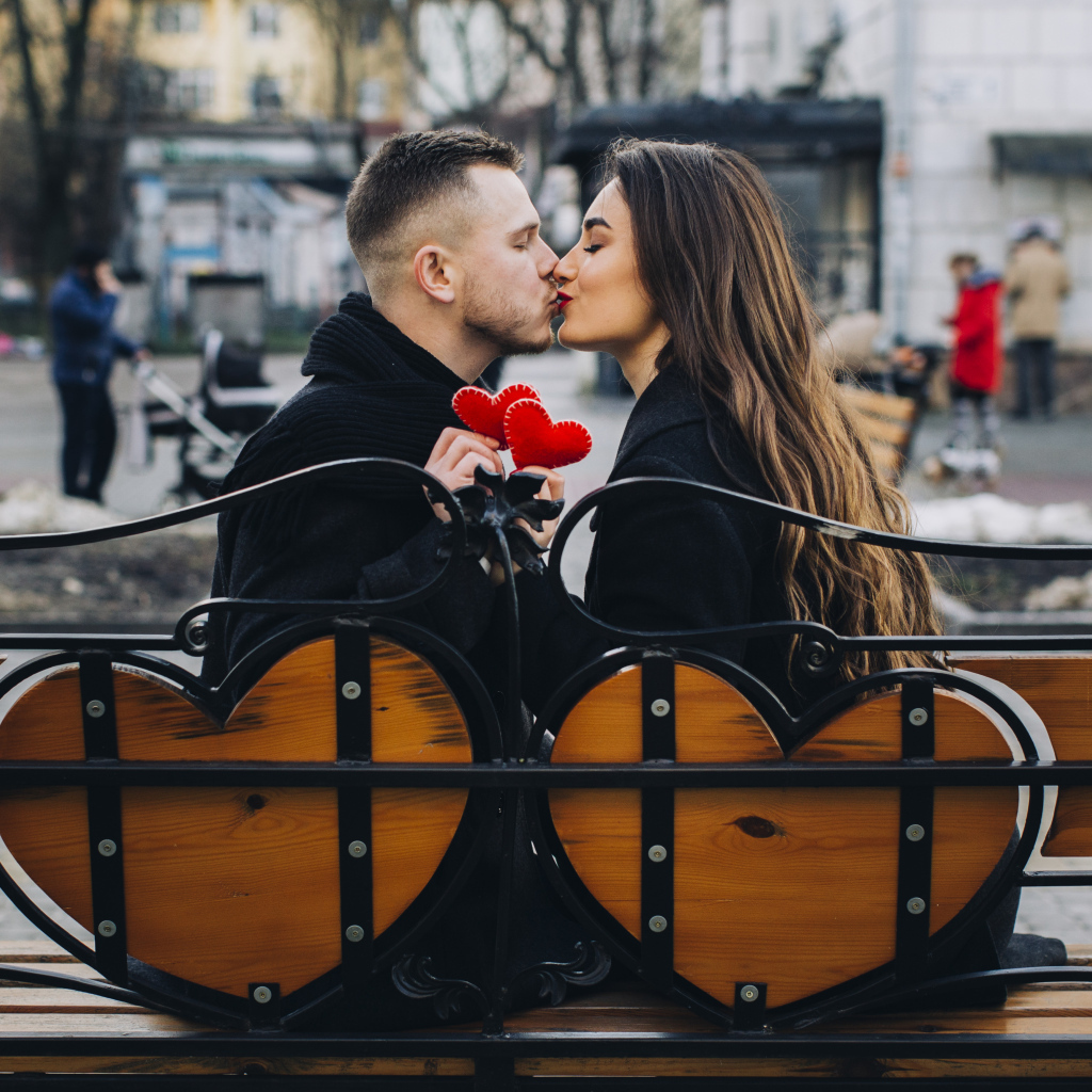 Поцелуй влюбленной пары на лавке в парке