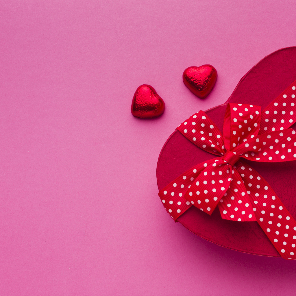 Большая красная коробка в форме сердца на розовом фоне