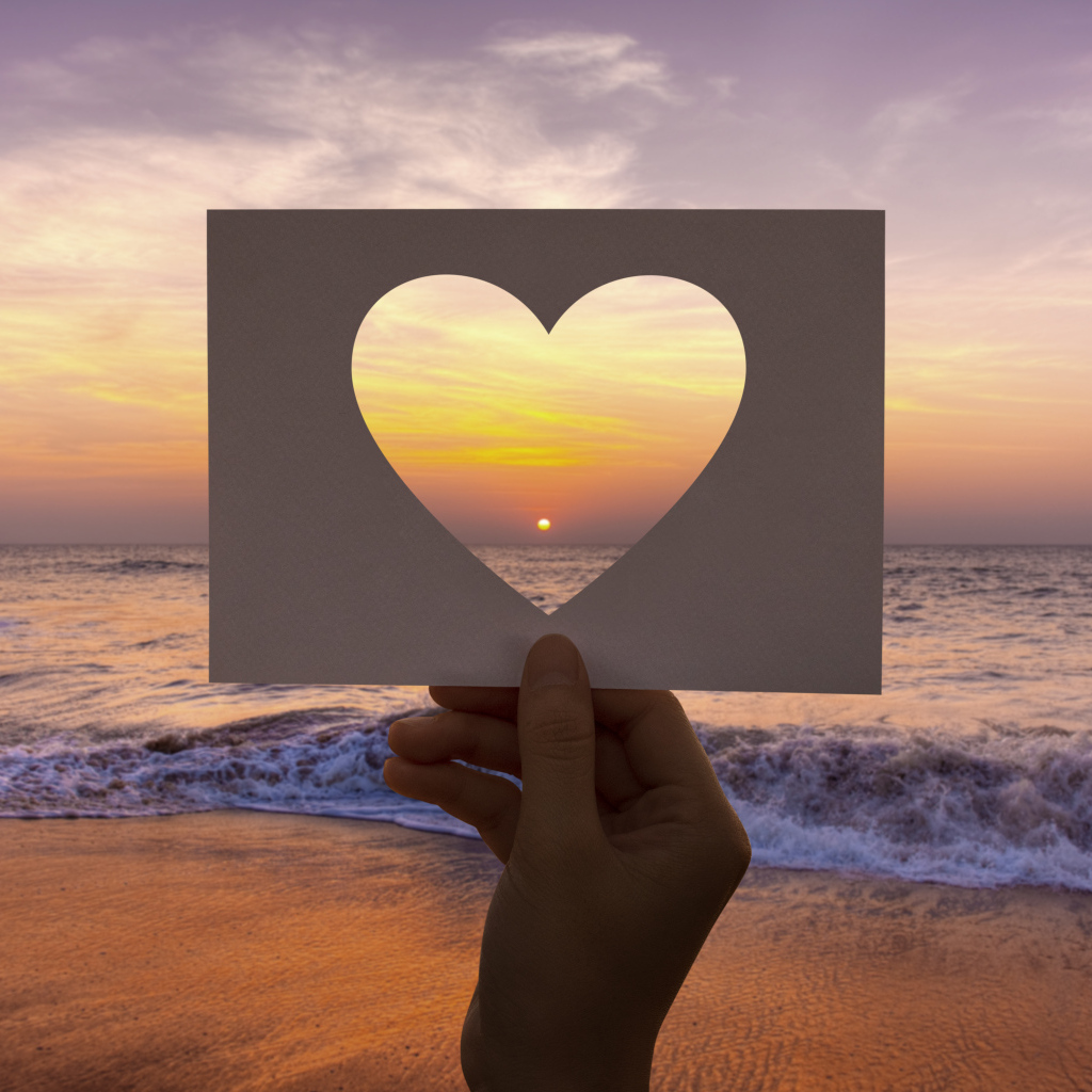 Бумажное сердце на фоне моря на закате солнца