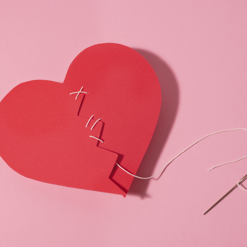 Бумажное сердце сшили нитками на розовом фоне