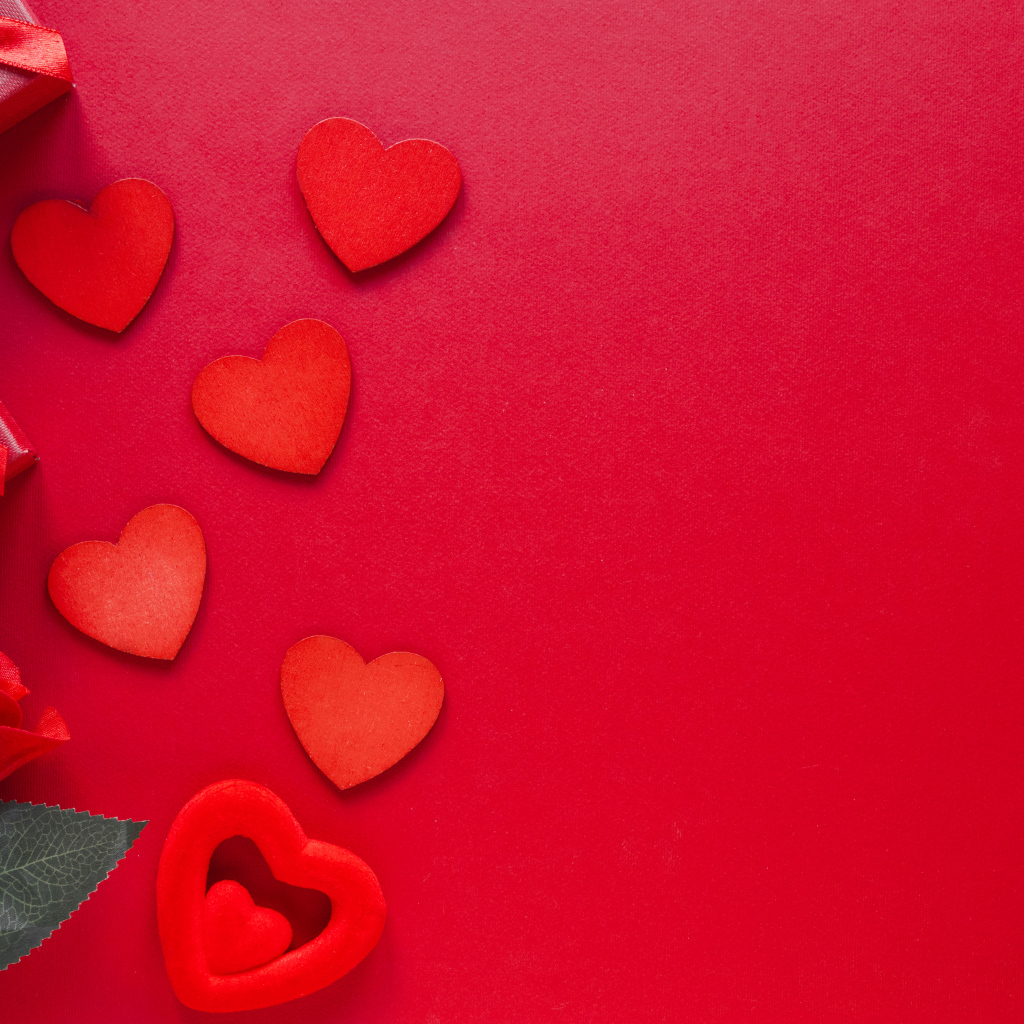 Бумажные сердечки с подарком и розой на красном фоне