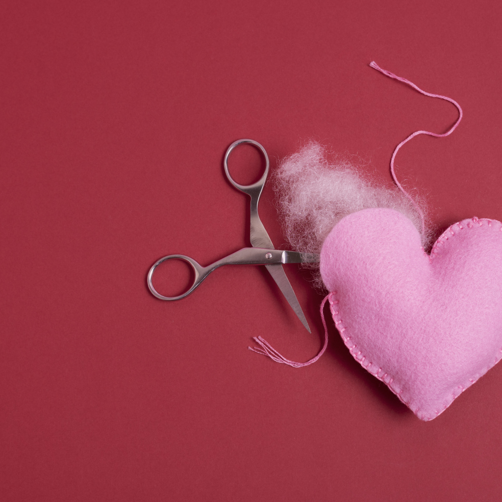 Розовое  сердце с ножницами на красном фоне