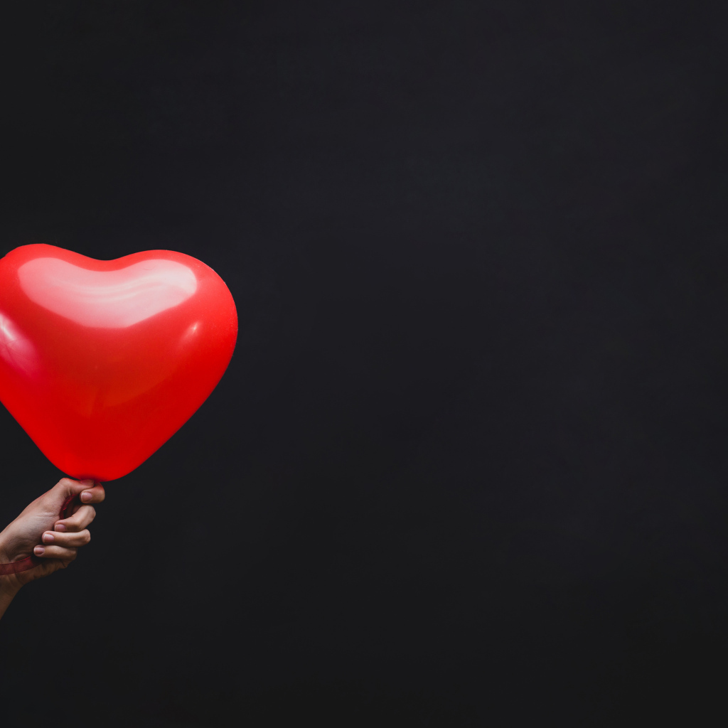 Красный шарик в форме сердца на черном фоне