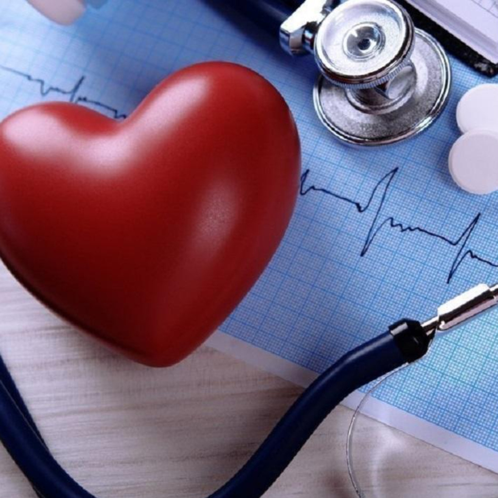 Красное сердце на столе с кардиограммой и стетоскопом