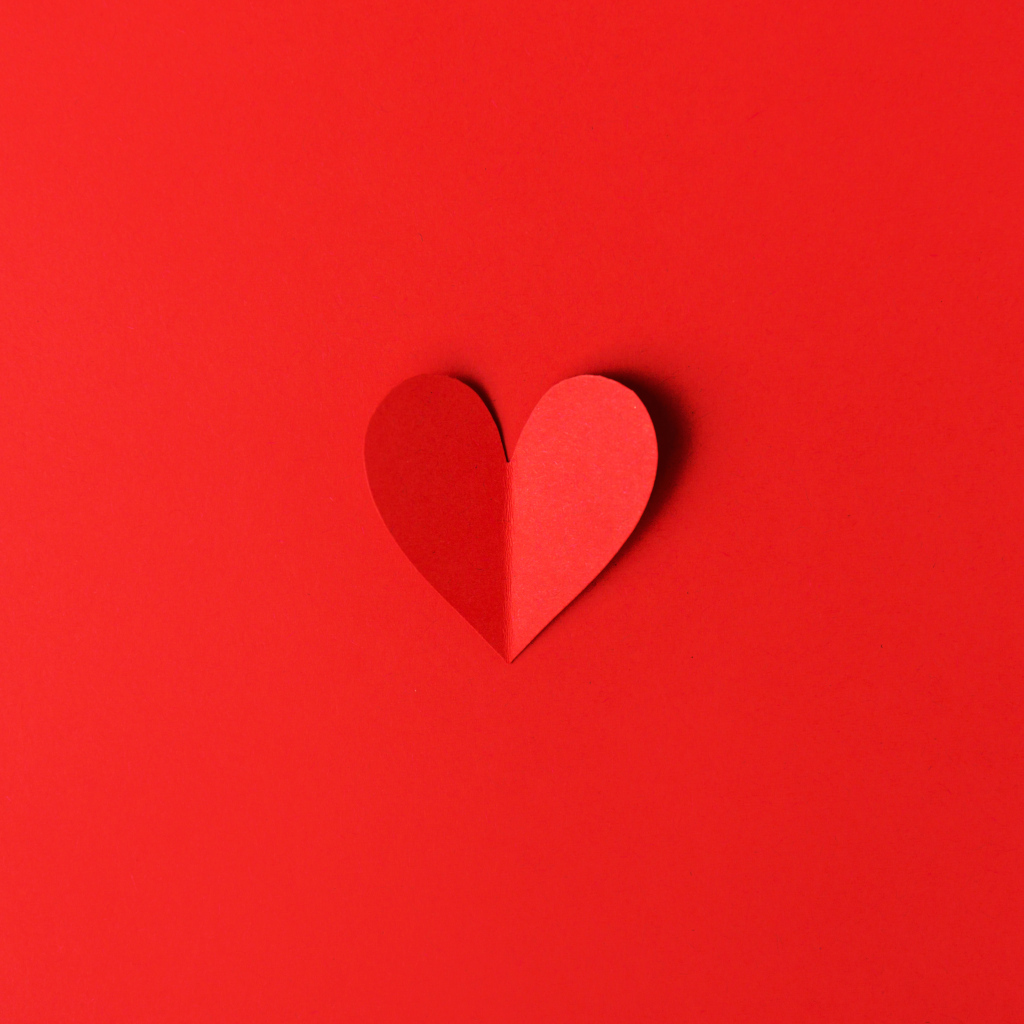 Маленькое бумажное сердце на красном фоне