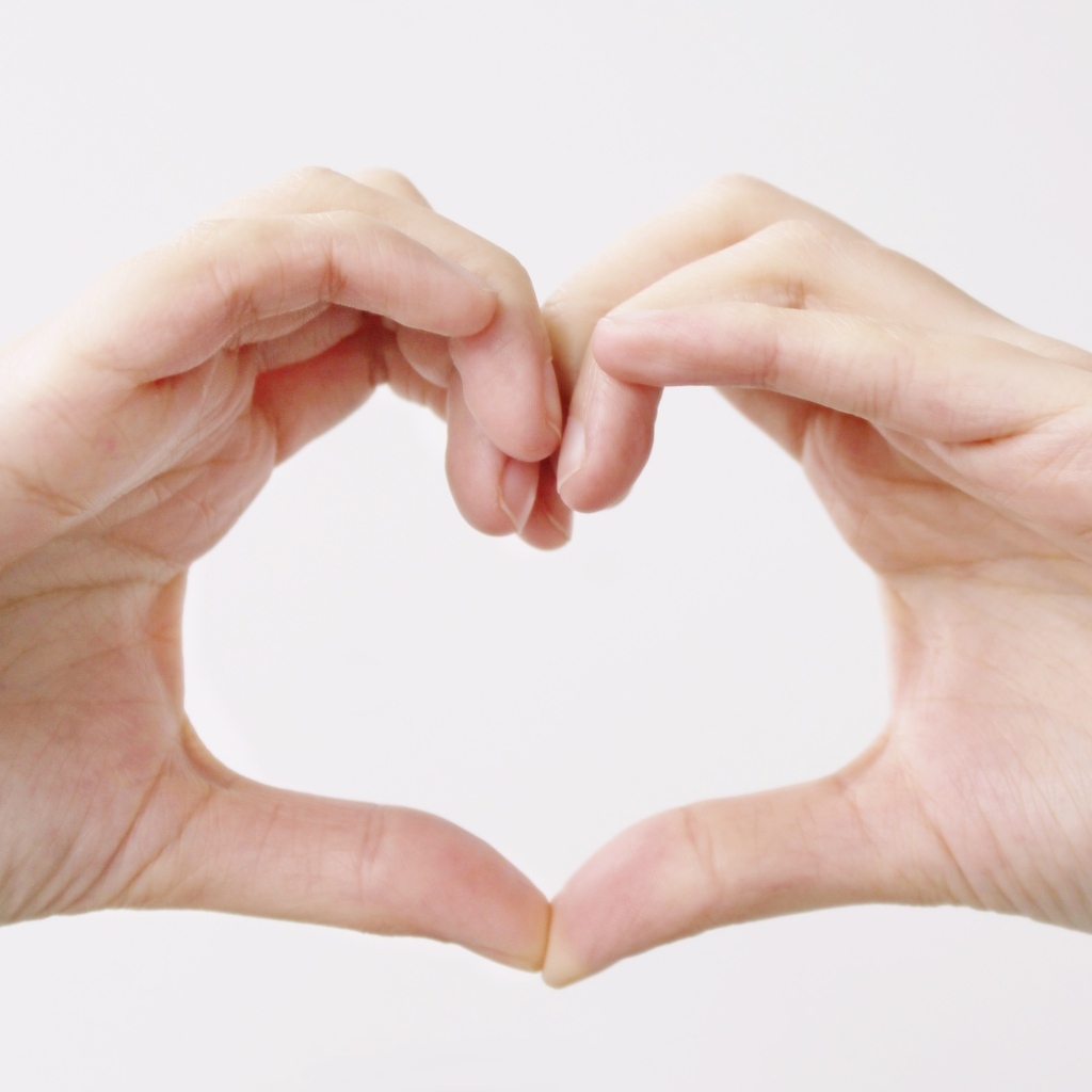 Две руки делают сердце на белом фоне