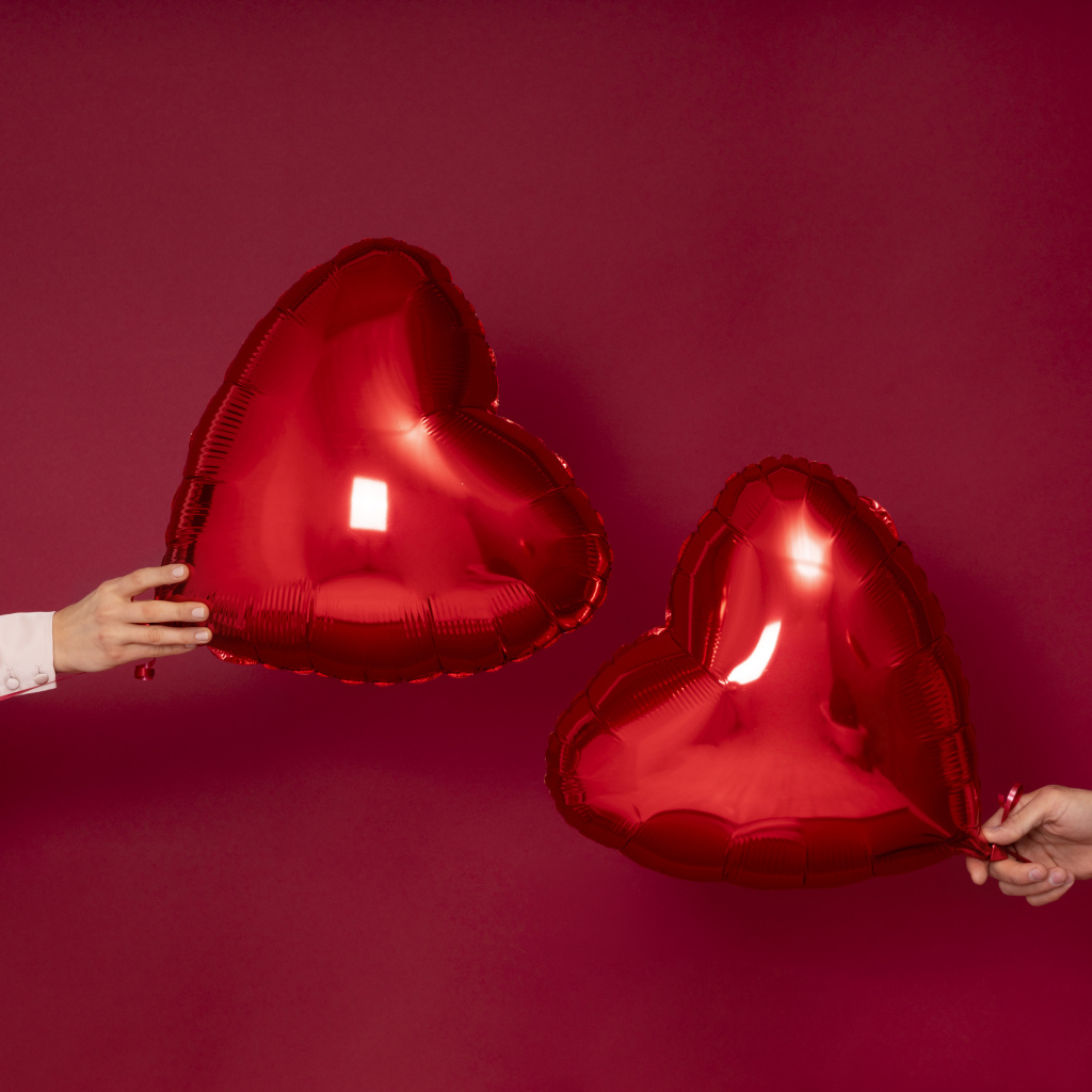 Два воздушных шара в форме сердца на красном фоне