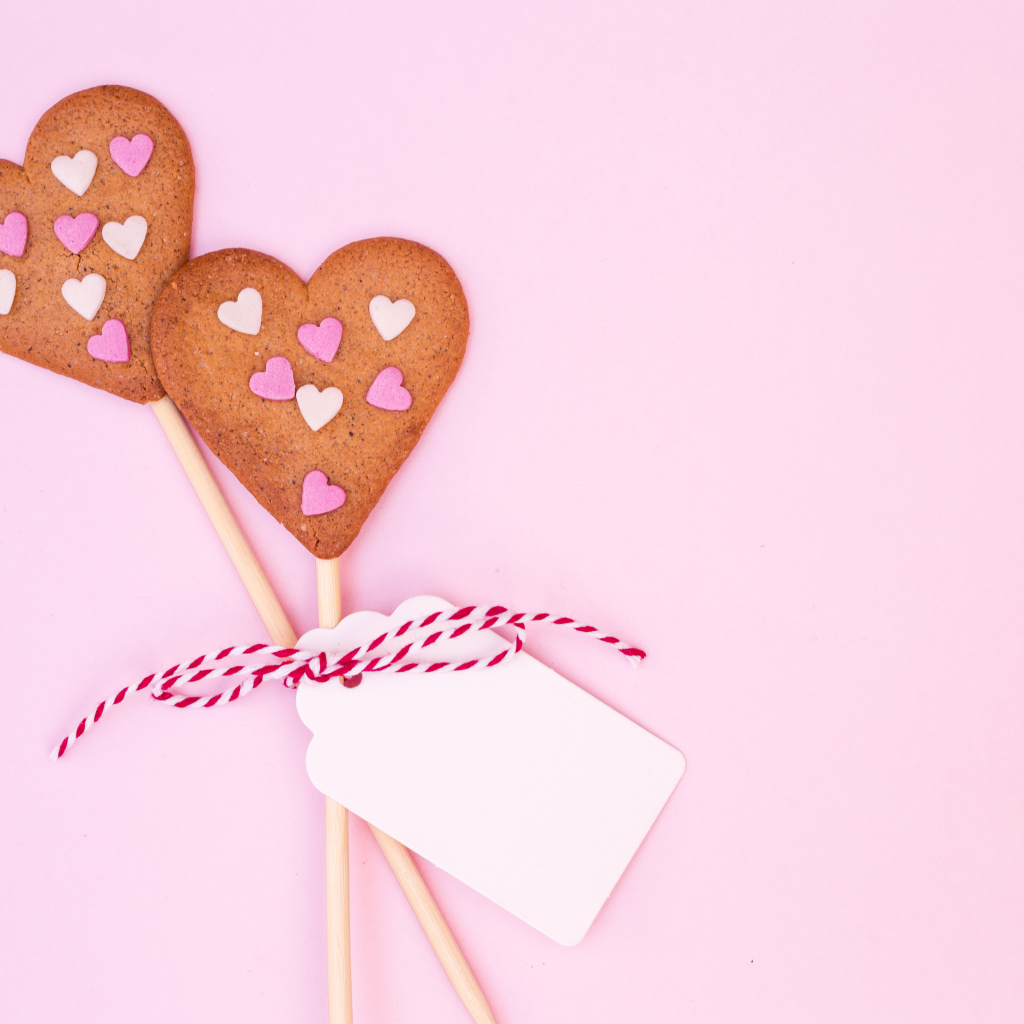 Два сердечка на палочке на розовом фоне