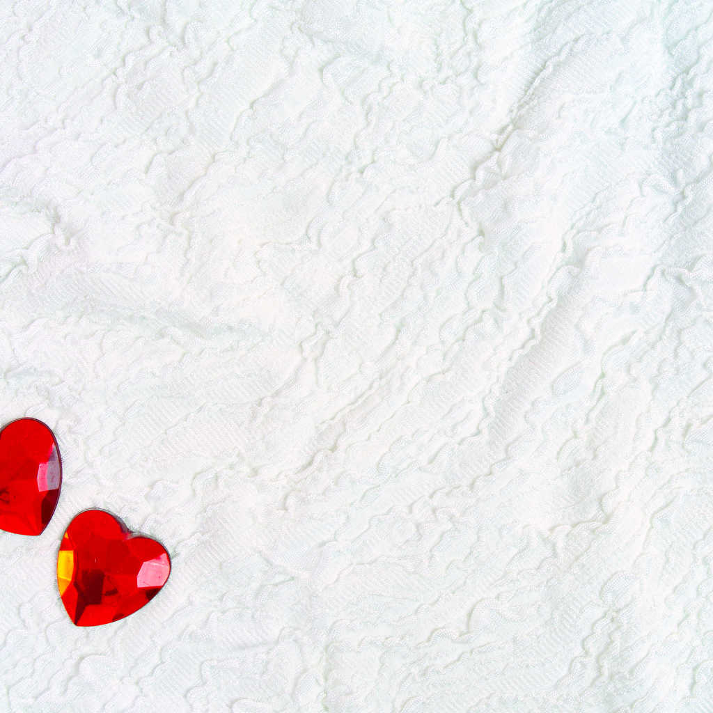 Два красных сердца из пластика на белой ткани