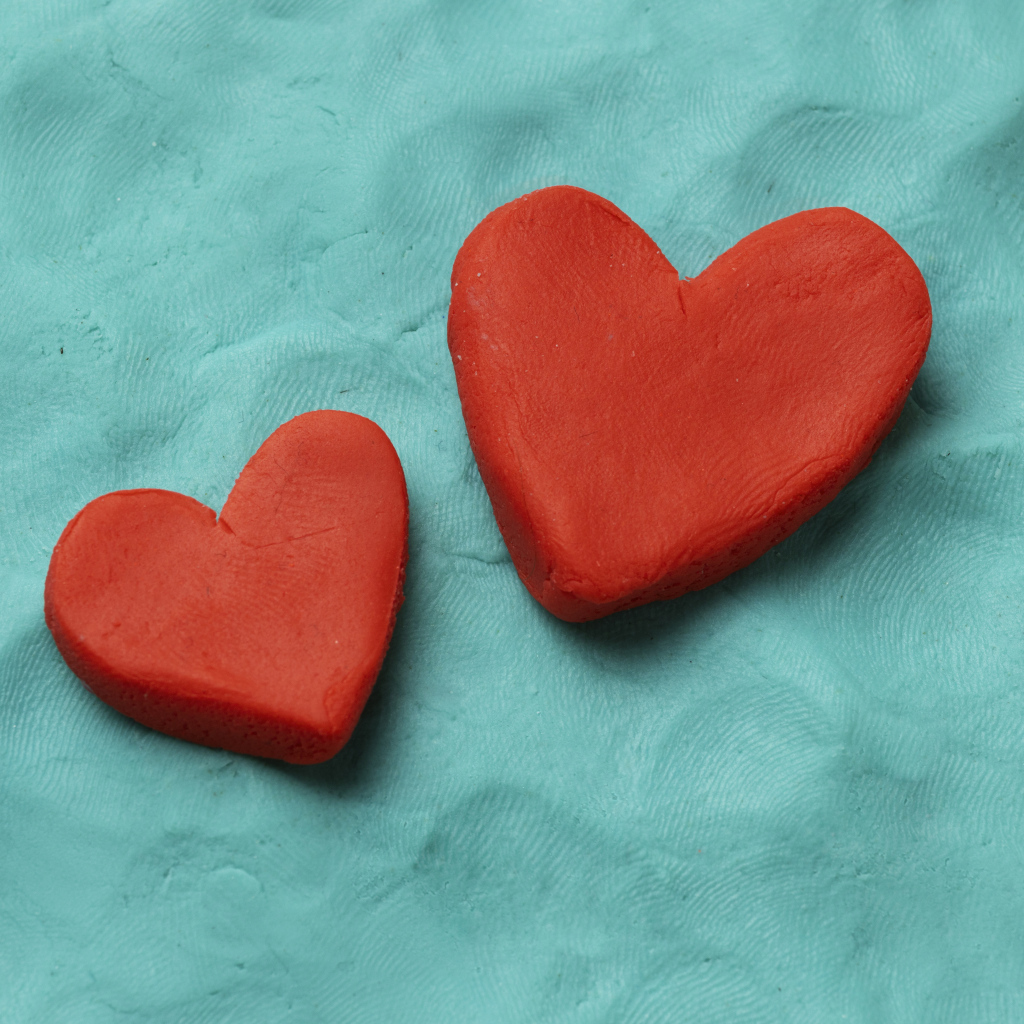 Два красных сердца из пластилина на голубом фоне