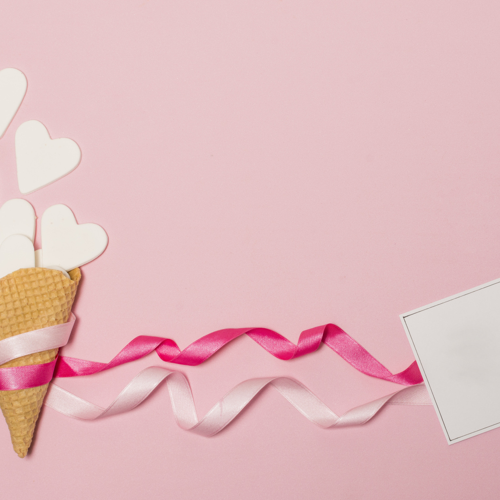 Вафельный рожок с сердечками, лентами и листом бумаги на розовом фоне