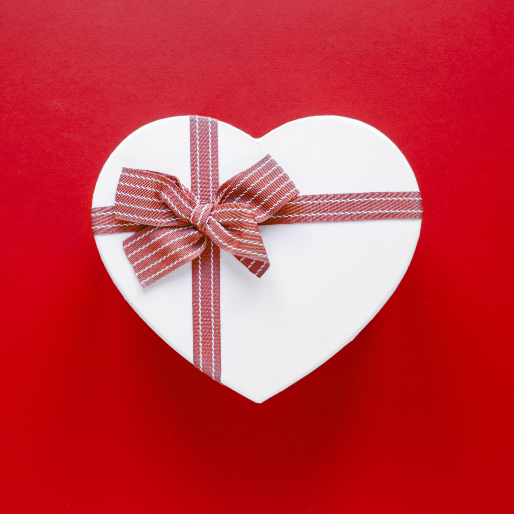 Белая коробка в форме сердца с бантом на красном фоне