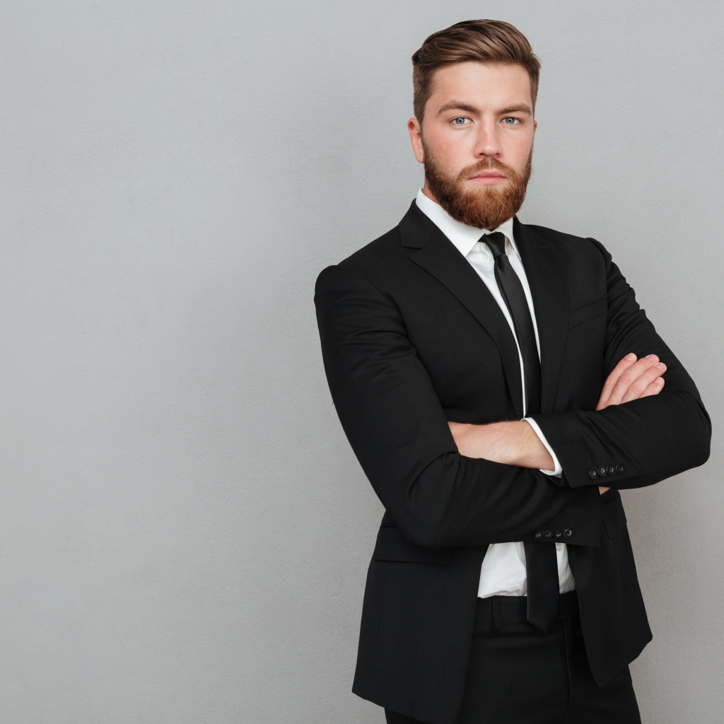 Деловой стильный мужчина в черном костюме на сером фоне