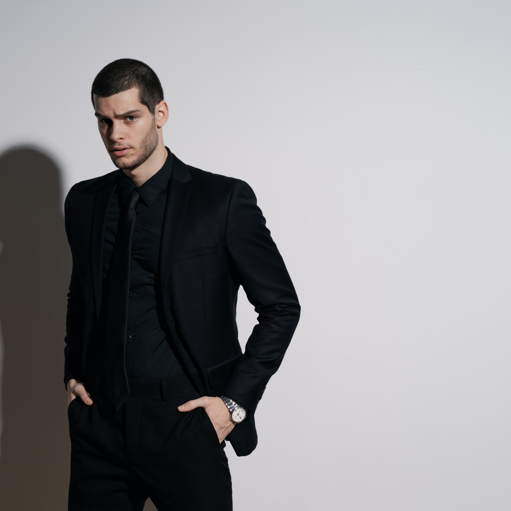 Красивый деловой мужчина стоит у серой стены