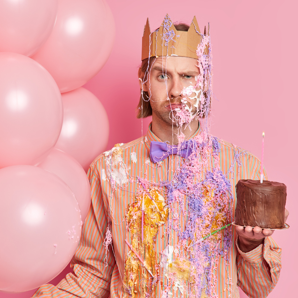 Мужчина принц с тортом и шариками на розовом фоне