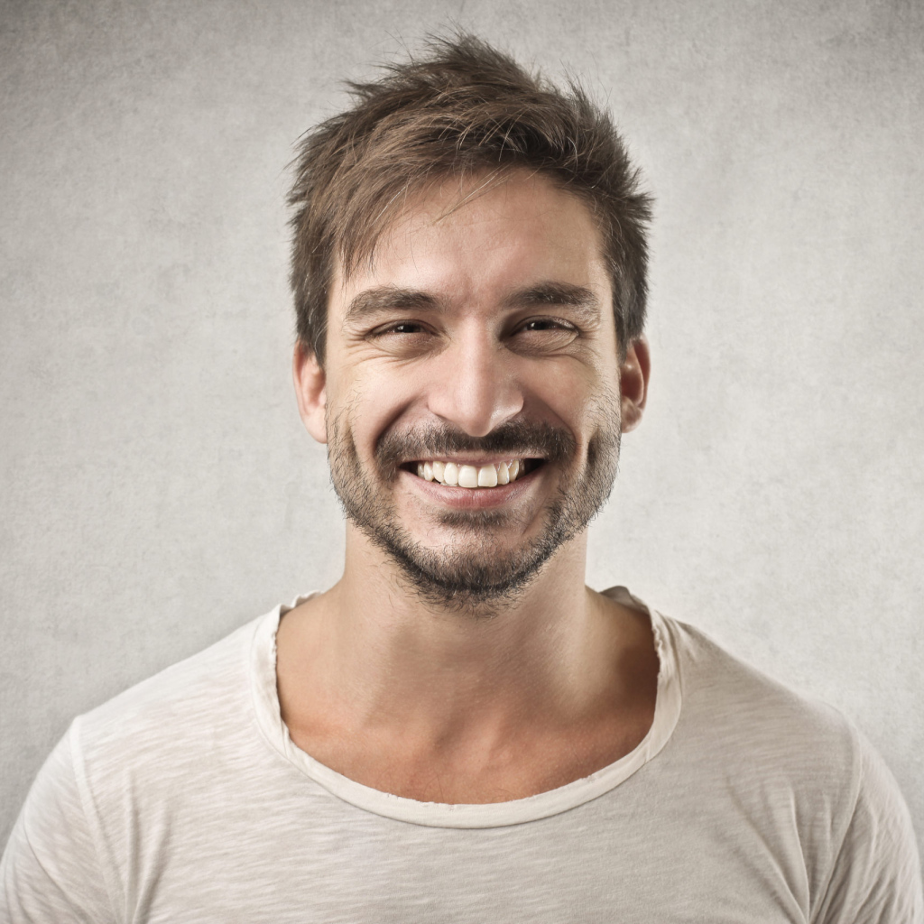 Улыбающийся мужчина в футболке на сером фоне